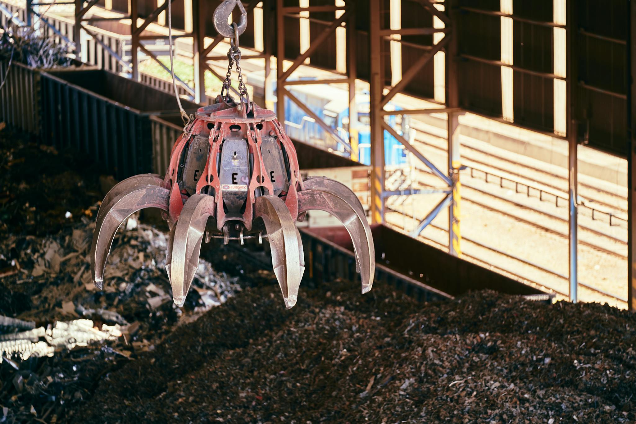 A claw crane inside a recycling facility lifting scrap metal, highlighting industrial processes.